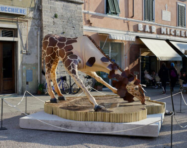 Bere era il momento più bello. Ma ogni giorno di più la foresta inaridiva e l’acqua diminuiva. Alice dovette piegarsi più in basso e successe: le sue bellissime macchie caddero. Rimase una giraffa nuda e avvilita.<br>
2021 Resina epossidica, ferro, smalti, materiali vari 380x300x280 cm.